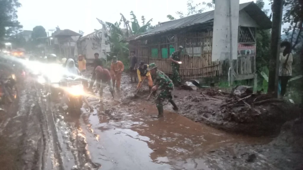 petugas TNI Polisi dibantu warga membersihkan lumpur di jalan